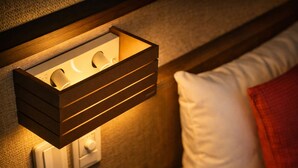 A wall-mounted light fixture with a wooden frame, a white pillow, and a red blanket on a bed. - AKARI Kyoto Gion (Kyoto)