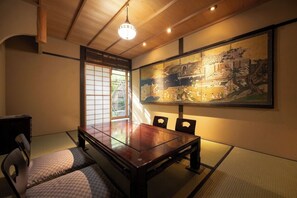 Een traditionele Japanse kamer met tatami vloerbedekking, een lage tafel en een groot schilderij aan de muur.