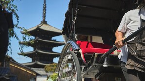 A traditional rickshaw with a red cover, a person holding the handle, and a pagoda in the background. - AKARI Kyoto Gion (Kyoto)