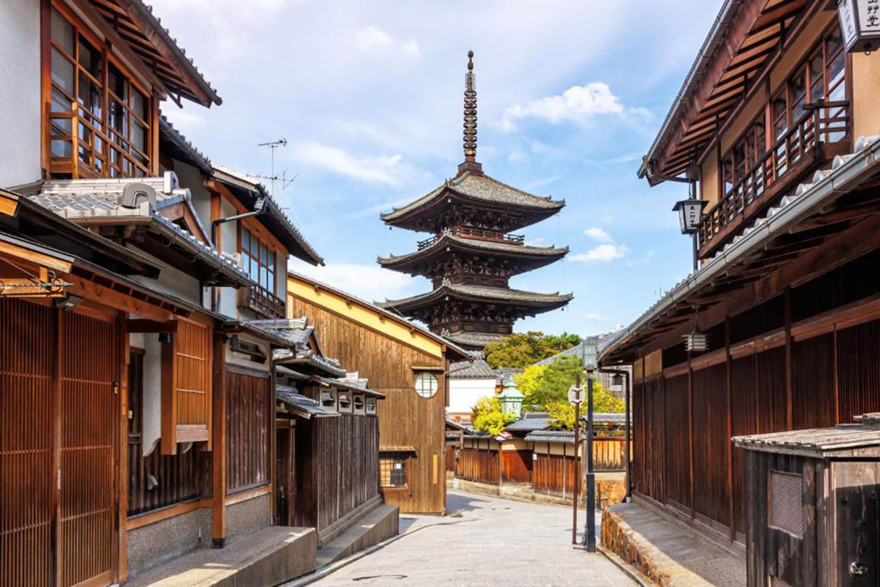 Una calle tradicional japonesa con edificios de madera y una pagoda.