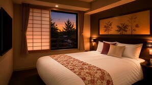 Una habitación de hotel con una cama grande, una ventana con cortinas, un cuadro en la pared y una mesita de noche con lámpara.