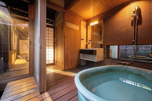 A traditional Japanese-style bathroom with a wooden interior, a large bathtub, and a sliding door leading to a separate room. - AKARI Kyoto Gion (Kyoto)