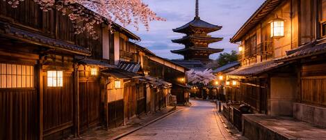 A traditional Japanese street with wooden buildings, a pagoda, and cherry blossoms.