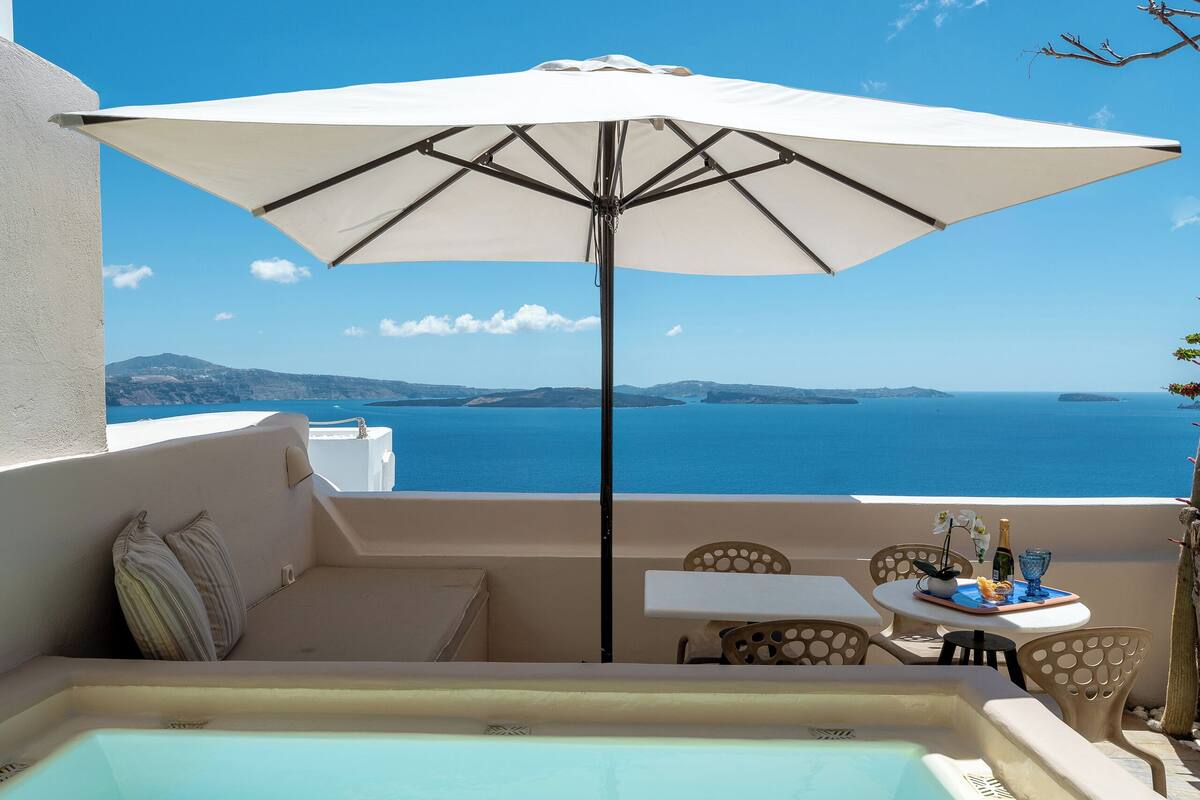 Un jacuzzi con vistas al mar, una mesa con sillas y un paraguas.