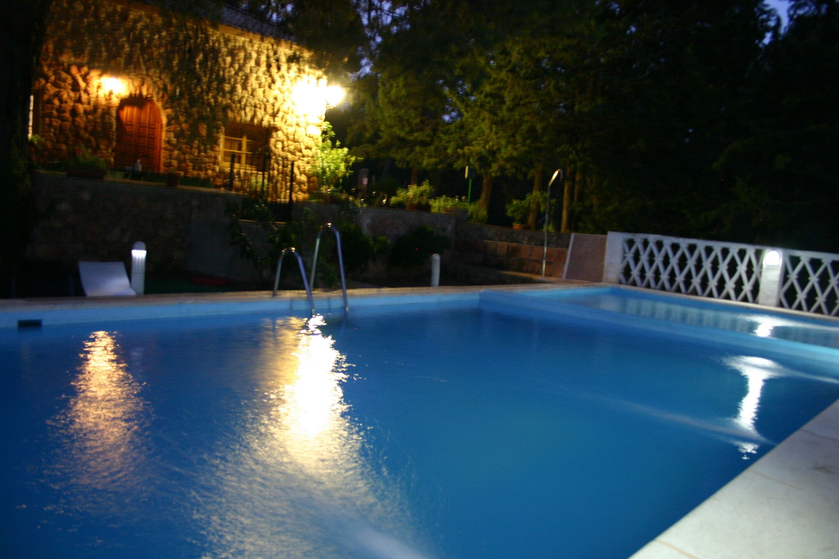 Una piscina con pared de piedra y muelle de madera.