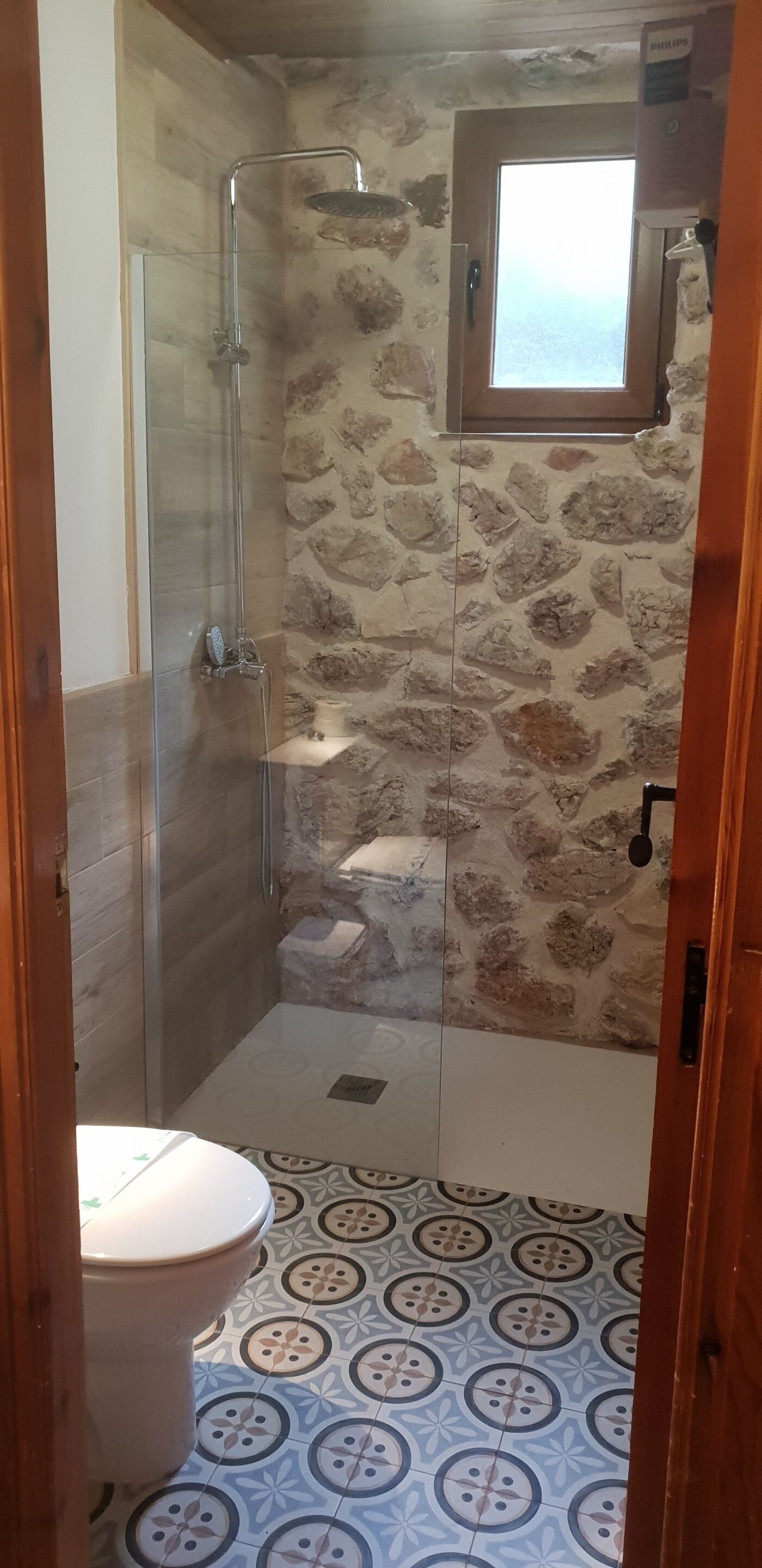 Un baño con ducha, inodoro y una ventana pequeña.