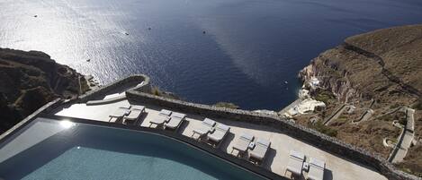 Una piscina al aire libre, una piscina con borde infinito, tumbonas