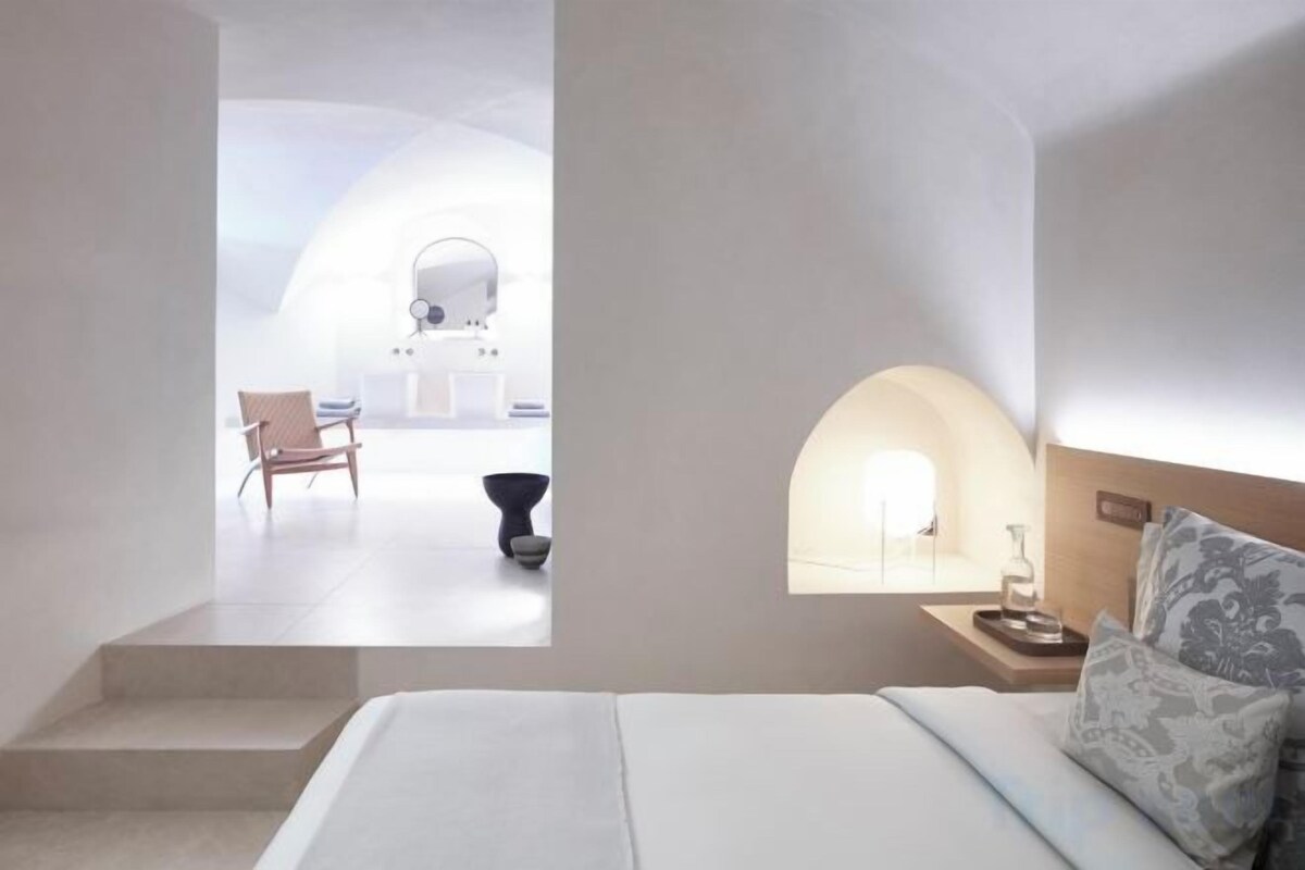 Una habitación de hotel moderna con una cama, una mesita de noche y vistas a un balcón.