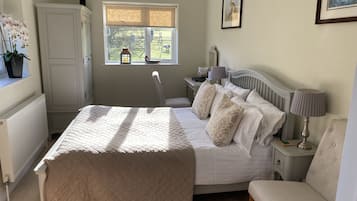 Une chambre à coucher comprenant un lit, des tables de chevet, une chaise, une fenêtre donnant sur l’extérieur et un radiateur.