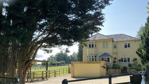 A large two-story house with a garage, surrounded by a fenced property with trees and a gravel driveway. - Sunny Nest (Cheltenham)