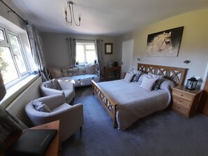 Une chambre à coucher avec un grand lit, un bureau, une chaise, une table de chevet et une fenêtre avec des rideaux.