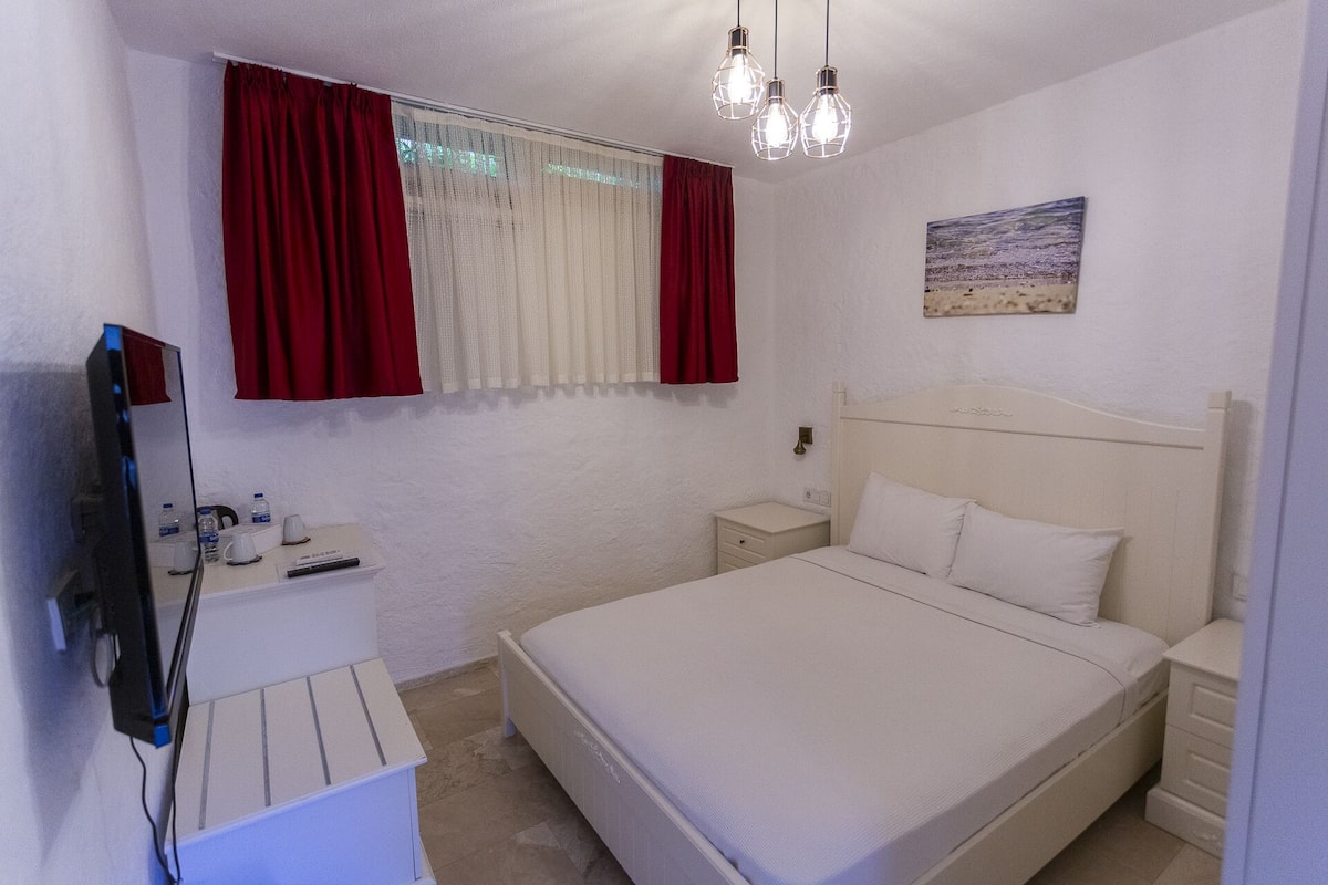 A bedroom with a bed, bedside tables, a TV, and a painting on the wall.