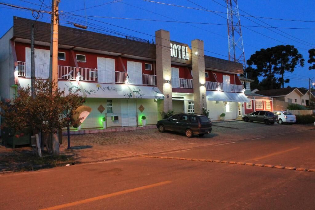 Un hotel de dos plantas con fachada roja y balcones blancos.