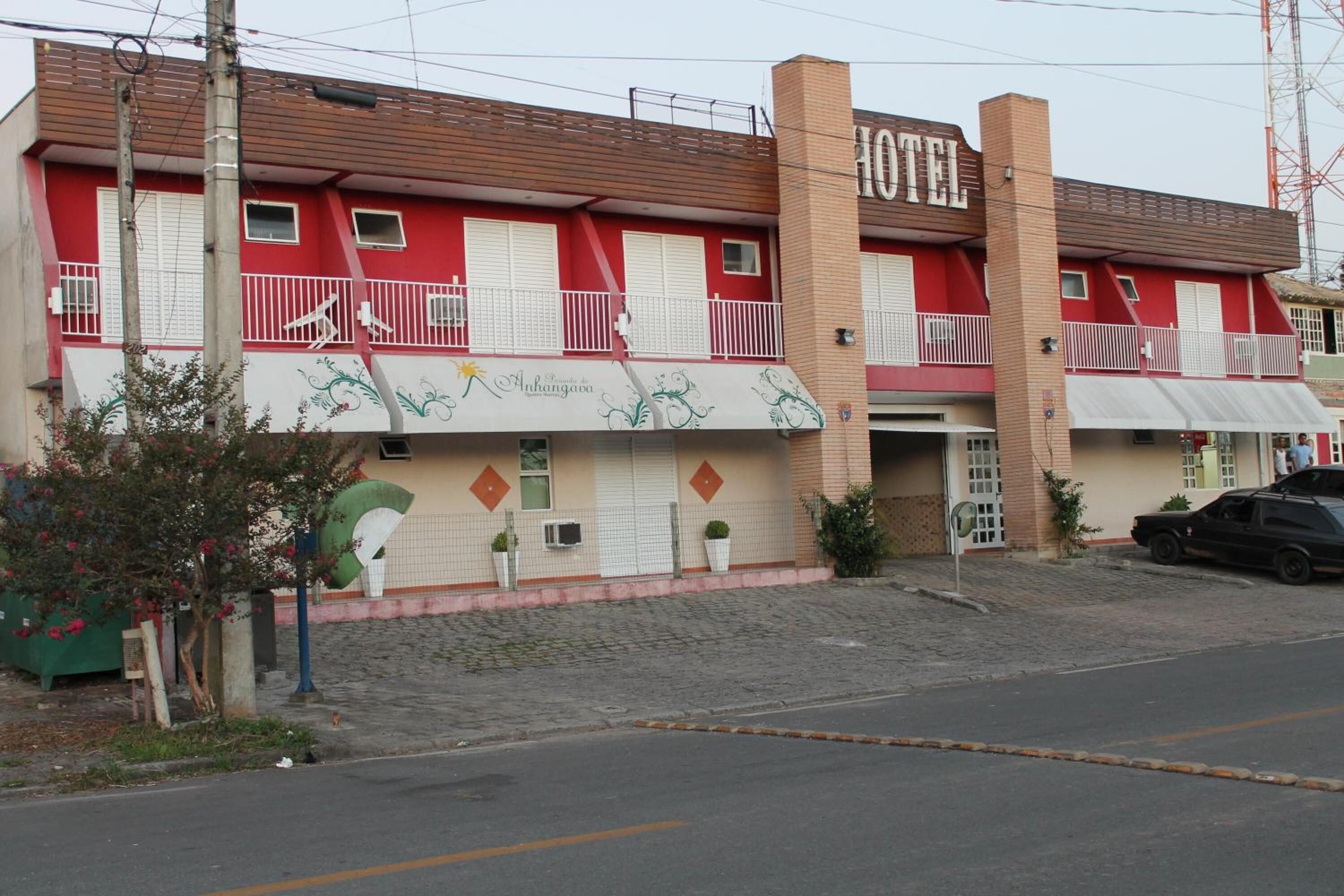A two-story building with a red facade, a balcony, and a sign that reads "HOTEL."