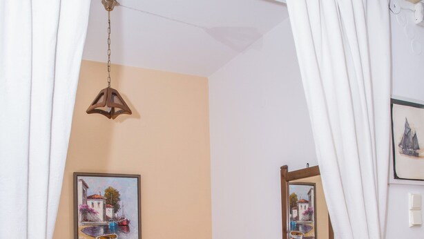 Quarto com cama, mesa de cabeceira, luminária e duas fotos emolduradas na parede.