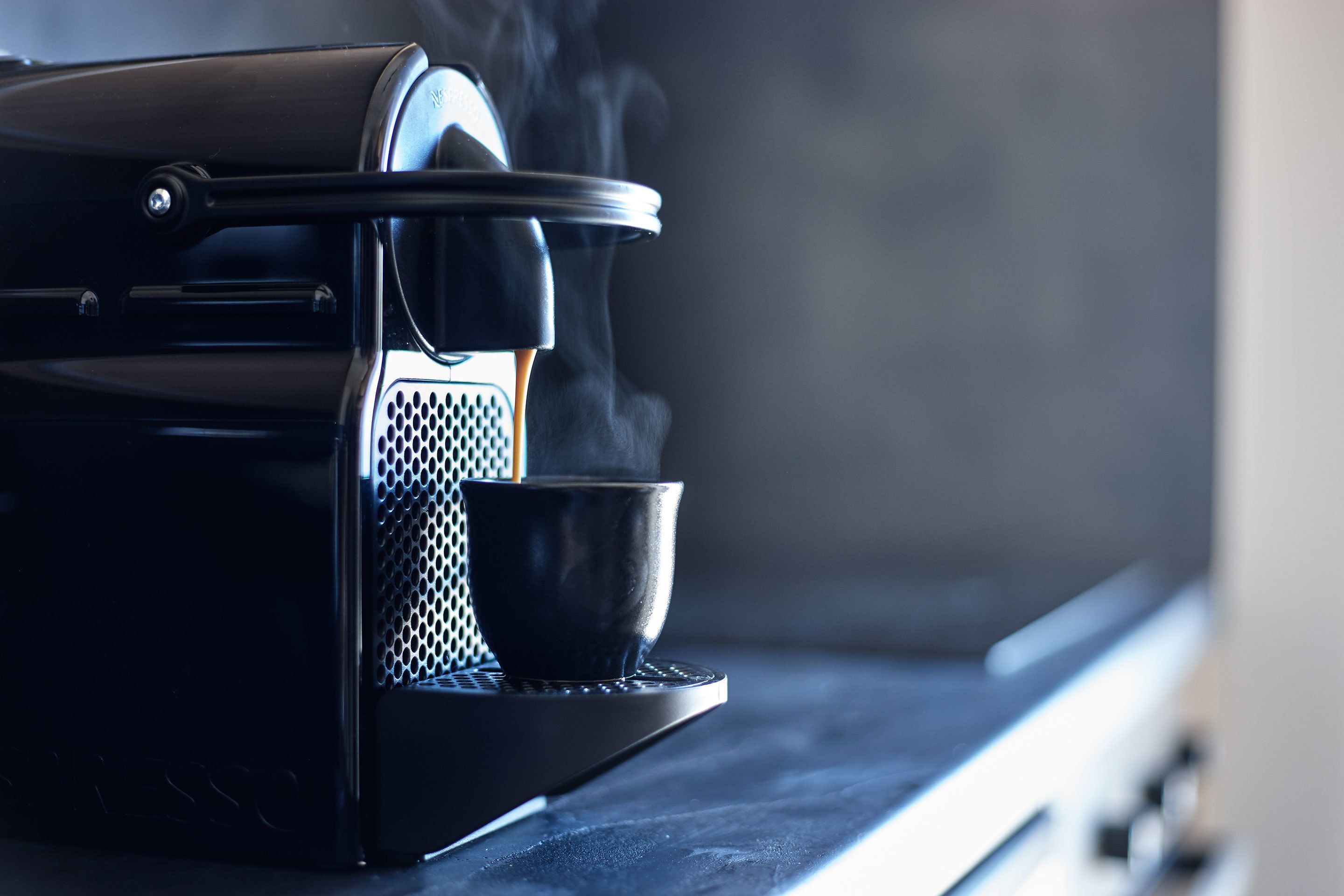 A coffee machine with a cup and steam.