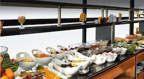 A buffet with various food items and a wine glass.