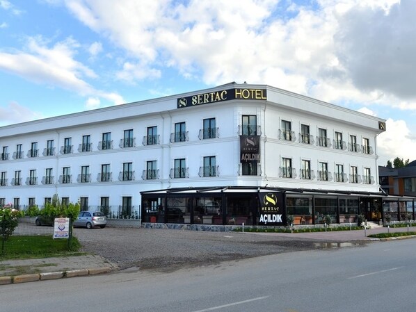 A white hotel with balconies and a sign reading "SERTAC HOTEL".