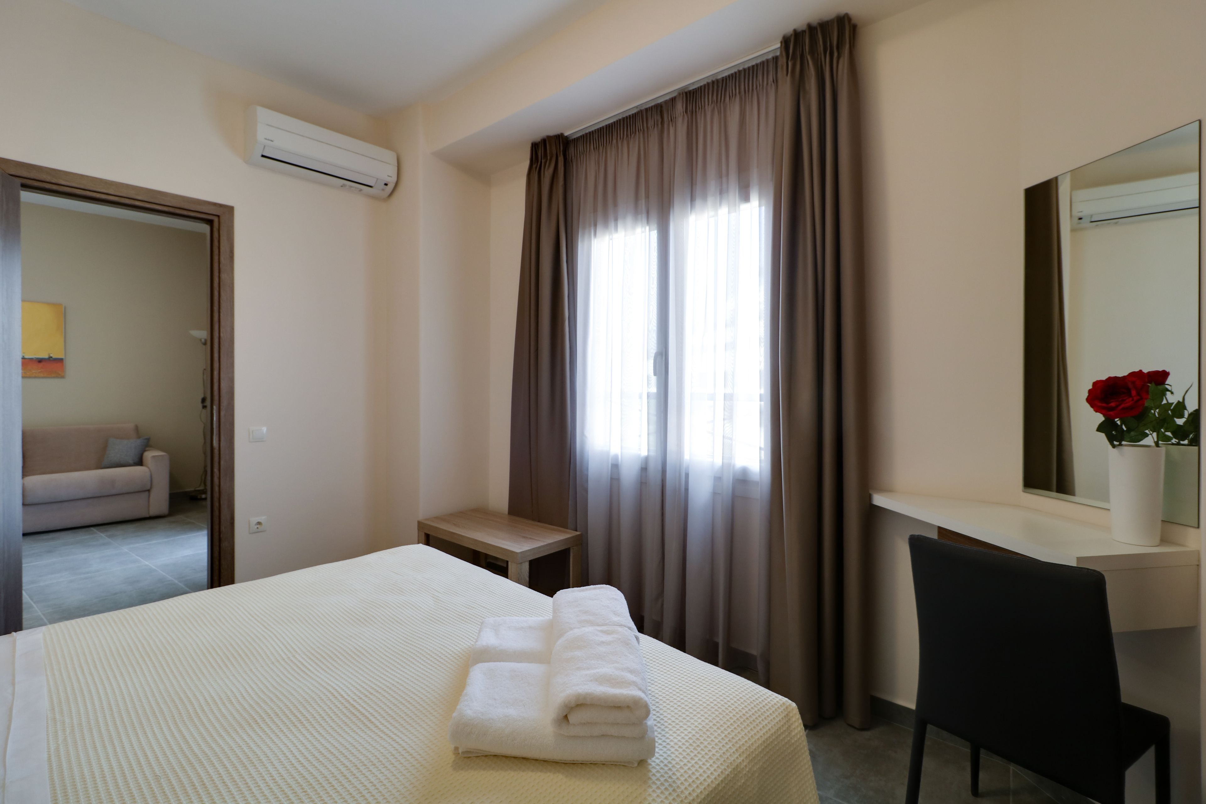 Une chambre d’hôtel comprenant un lit, un bureau, une chaise, une fenêtre avec des rideaux et un miroir.