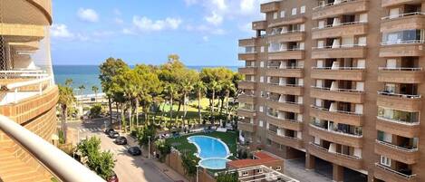 A multi-story building with a swimming pool and a view of the ocean.