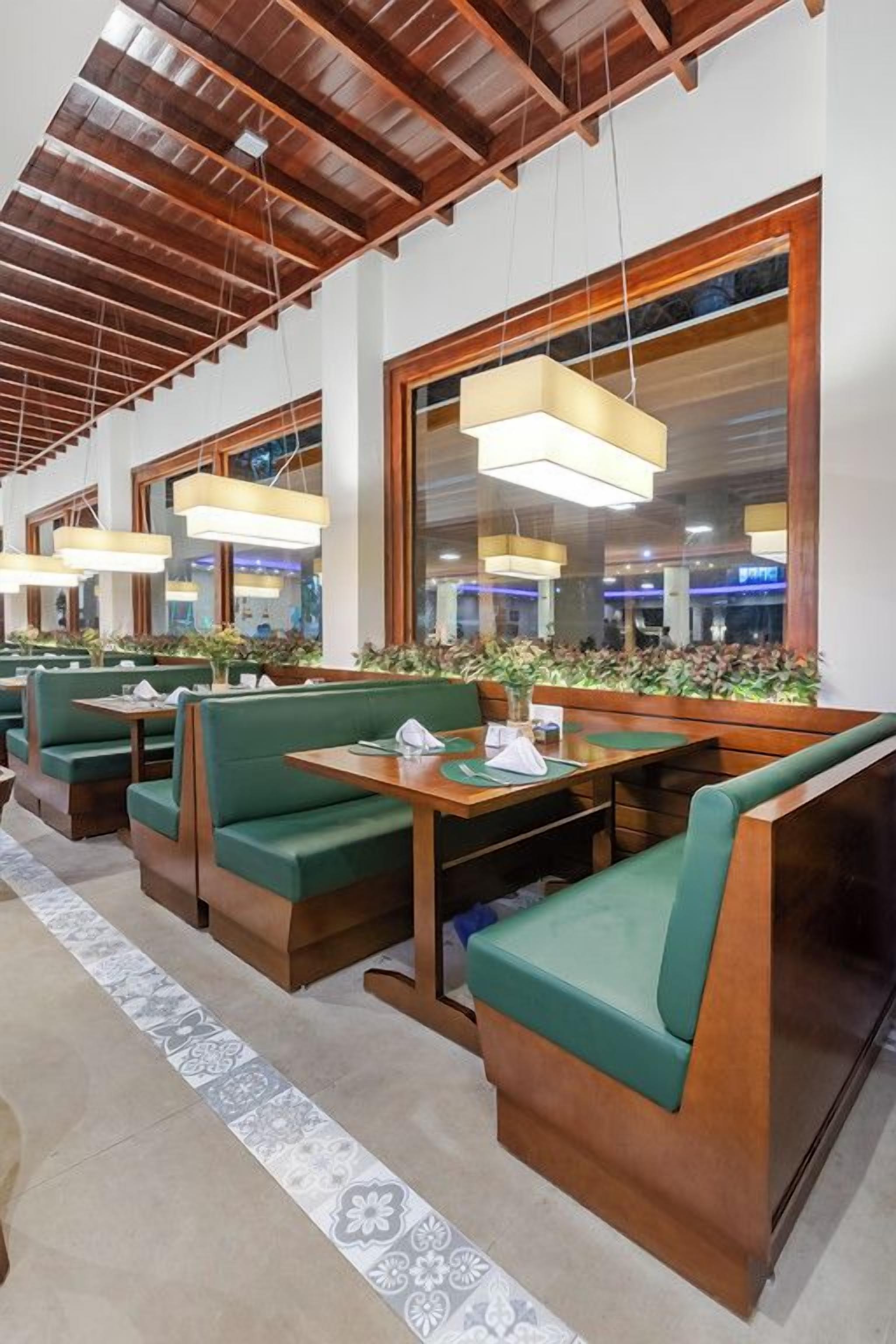 A restaurant with wooden booths, hanging pendant lights, and large windows.