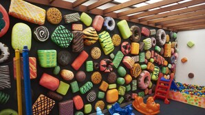 Een kleurrijke wand met objecten in verschillende vormen en texturen, een kleine glijbaan en een bällebad.
