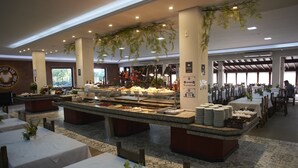 Een buffetgedeelte met verschillende food stations, tafels en stoelen klaar voor het diner.