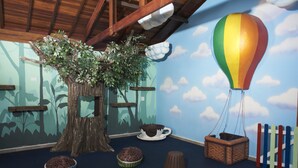 Une pièce avec un arbre, un ballon à air chaud et des tabourets.