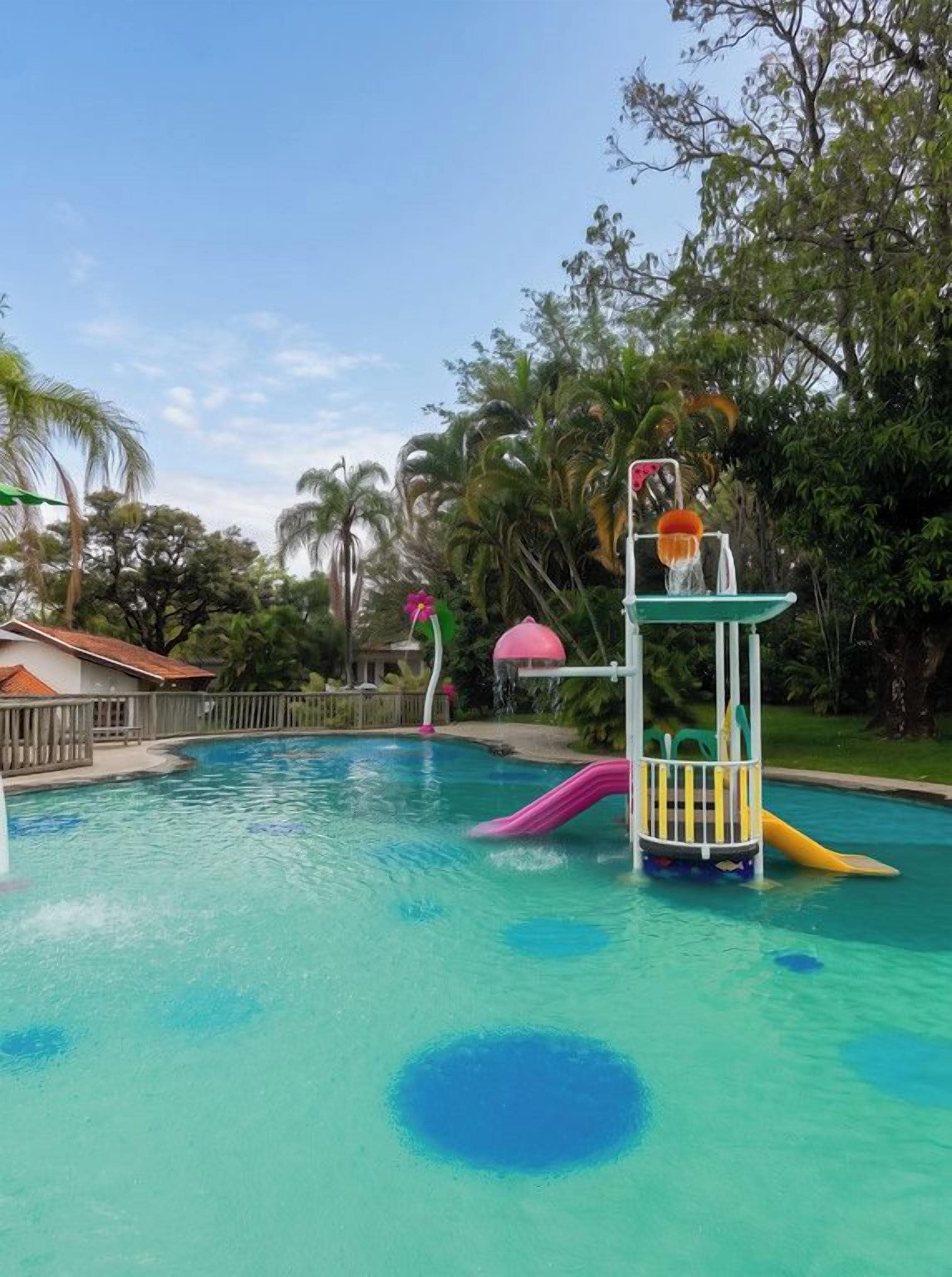 En swimmingpool med en vattenrutschkana och en liten lekplats.