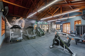 Een fitnessruimte met loopbanden, elliptische trainers en gewichten.