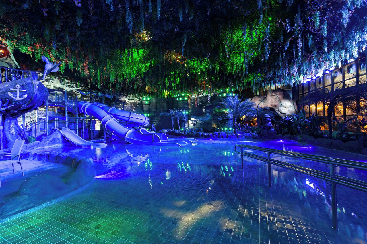 Un parque acuático interior con toboganes y una zona de piscina.