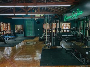 Ein Fitnessstudio mit verschiedenen Trainingsgeräten, einer Neonreklame und einer Holzzieldecke.
