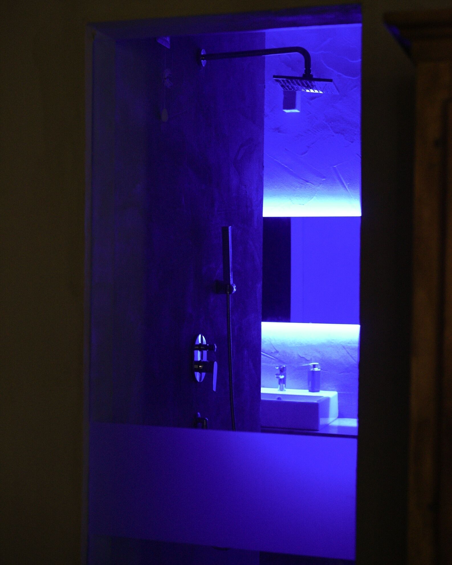 A bathroom with a blue-lit shower area and a visible sink.