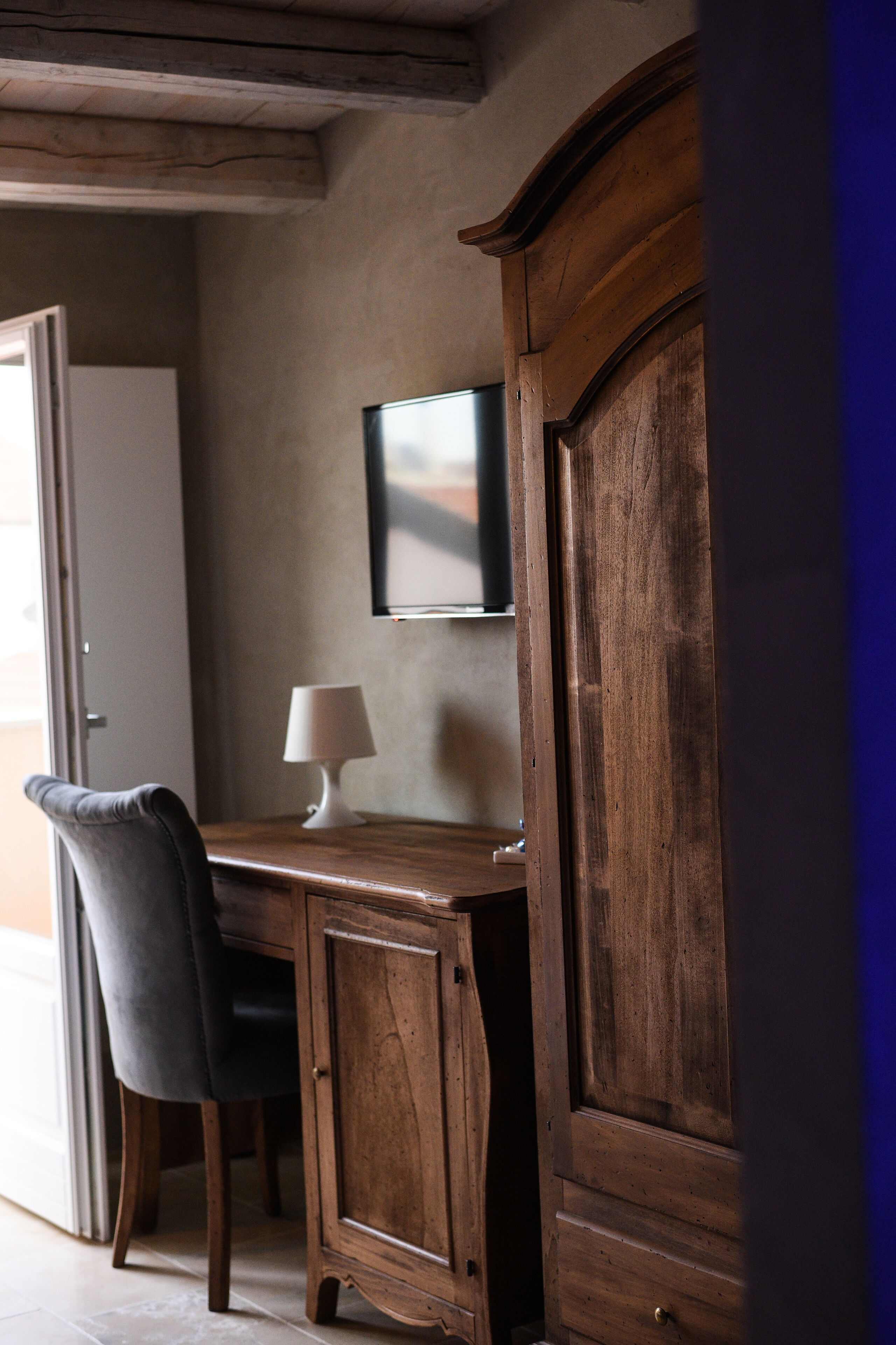 Un bureau en bois, une chaise, une lampe et un téléviseur fixé au mur.