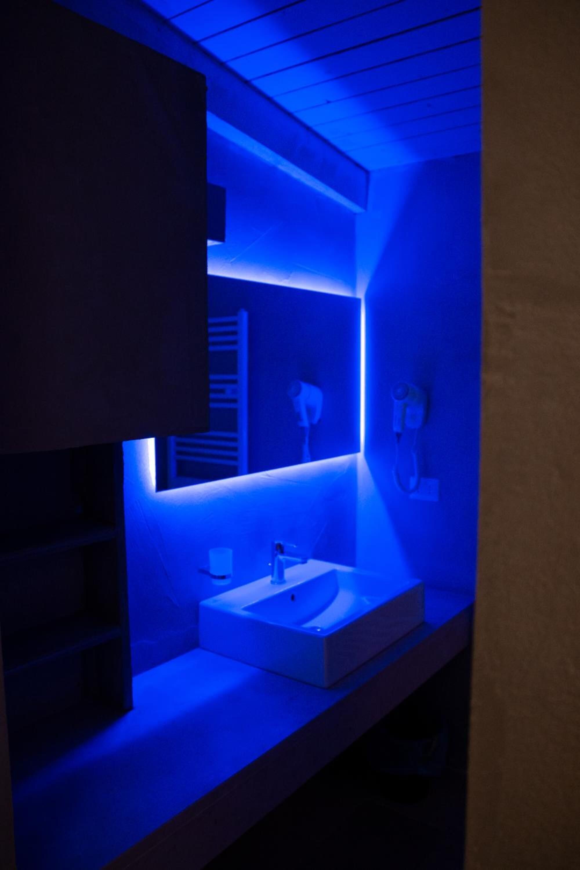 A modern bathroom with a blue-lit vanity, a sink, and a mirror.