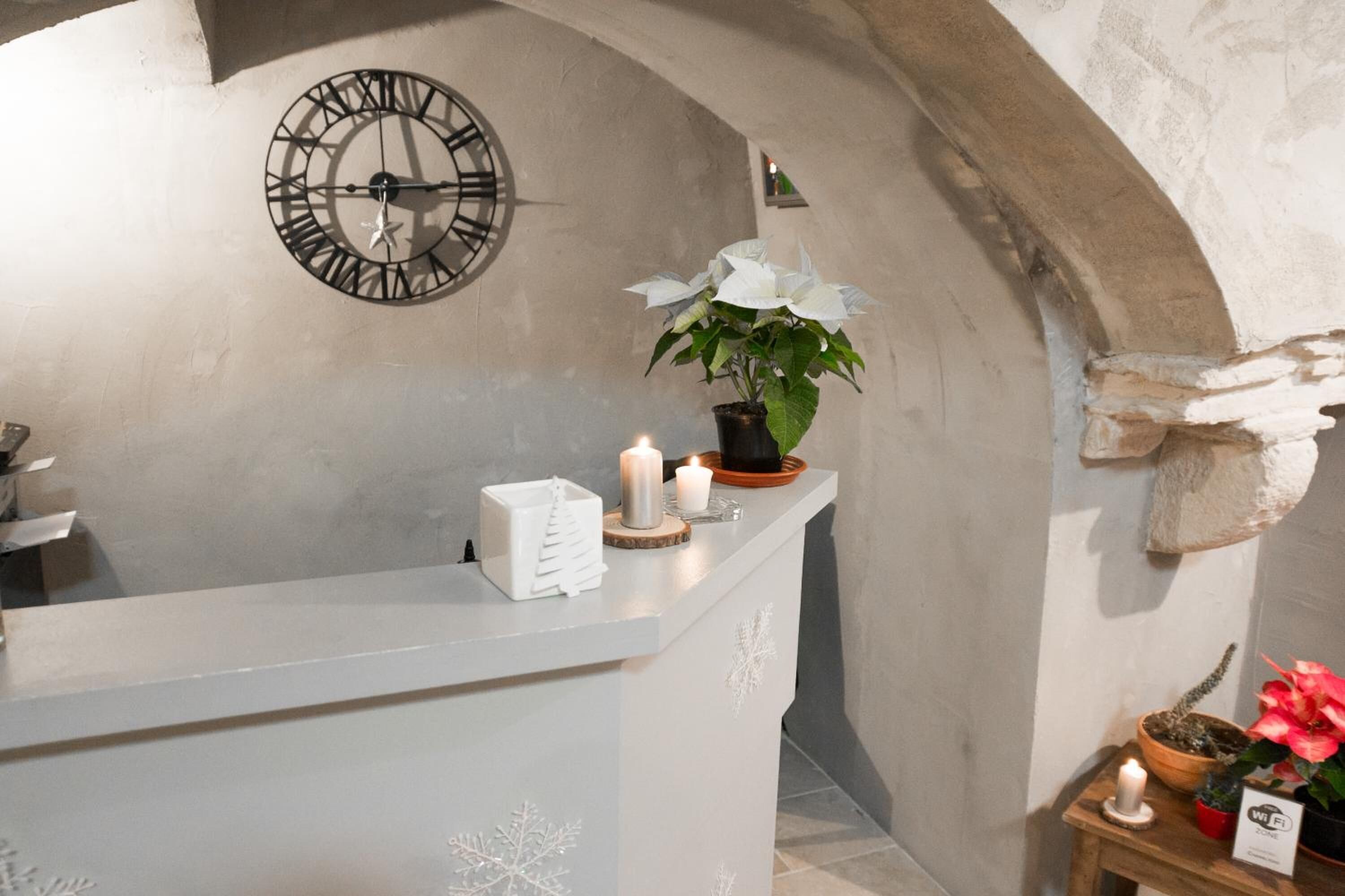 A reception area with a clock, a plant, candles, and a small table with a WiFi sign.