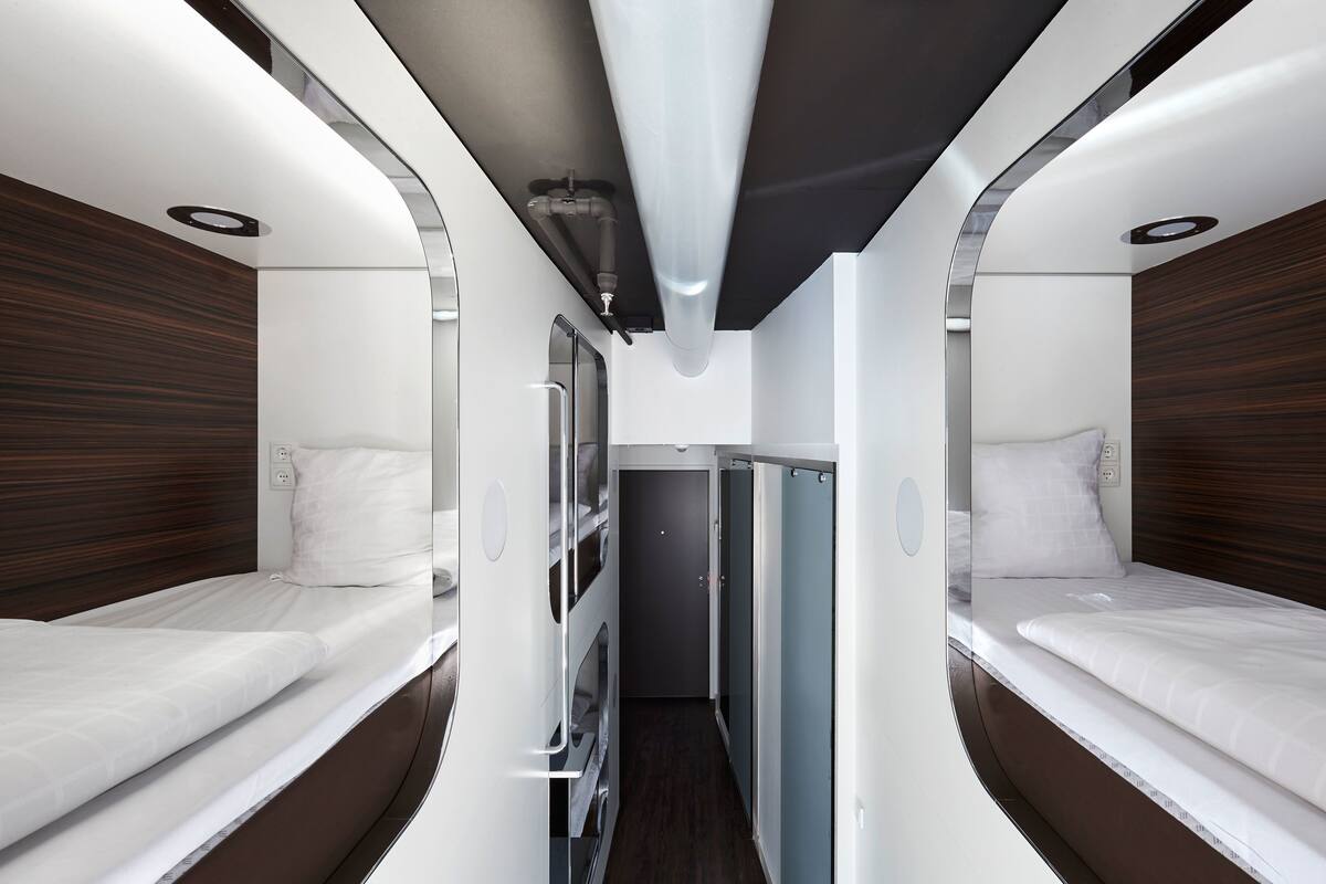 A train compartment with two beds, a small corridor, and a window.