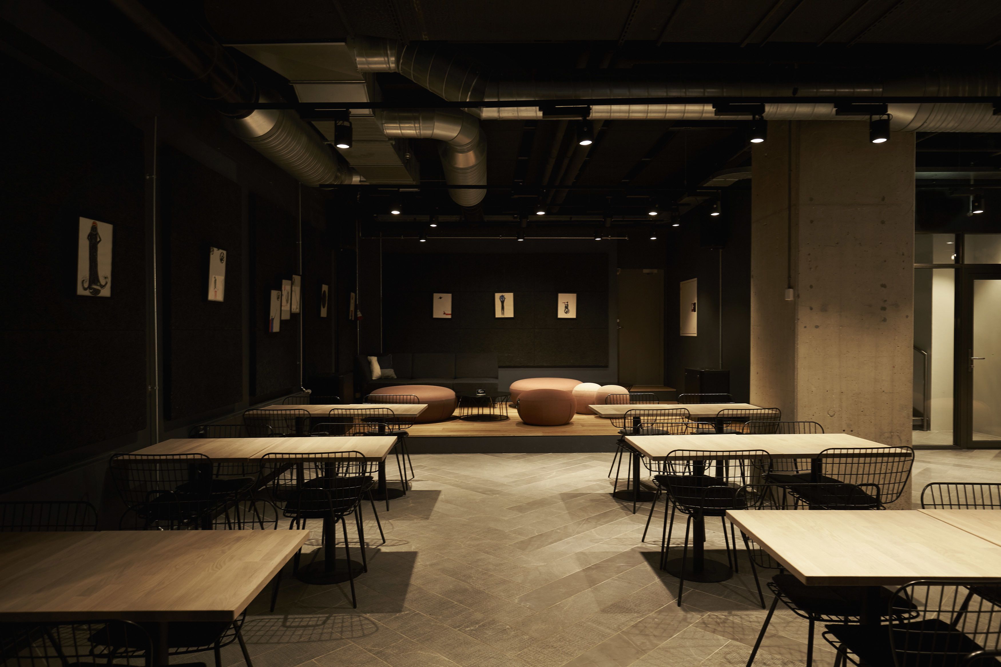 A modern conference room with tables and chairs, a central seating area, and visible ventilation ducts.