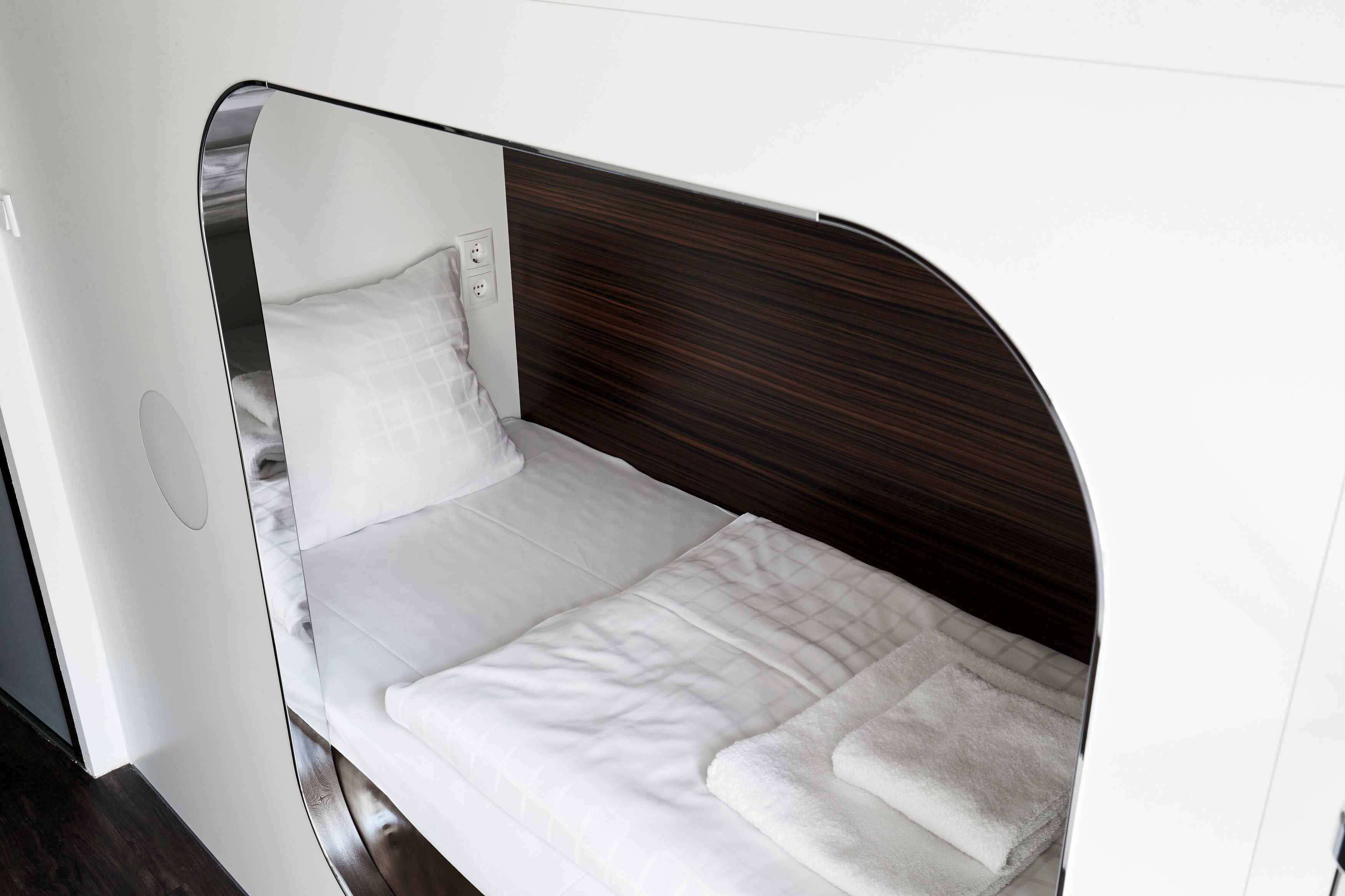 Ein kleines, modernes Bett mit Holz Kopfteil und weißer Bettwäsche.