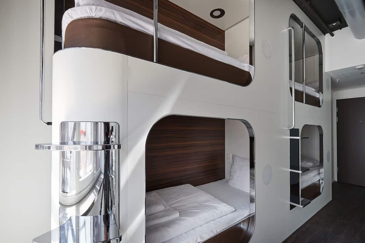 A bunk bed with a wooden headboard, a small window, and a mirror.