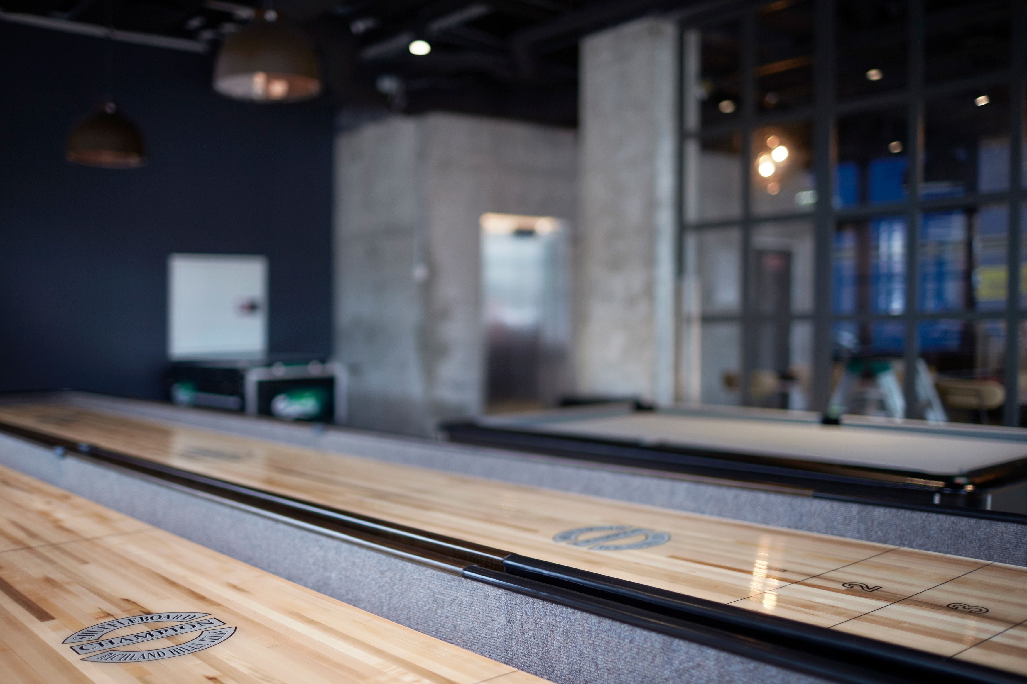 Een bowlingbaan met een houten baan, een automatische pinzetter en een glazen wand met reflecties.
