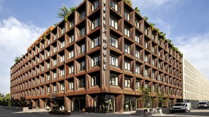 Un bâtiment moderne doté d’une façade à motifs géométriques, avec des fenêtres et des balcons, et d’un espace commercial au niveau du rez-de-chaussée.