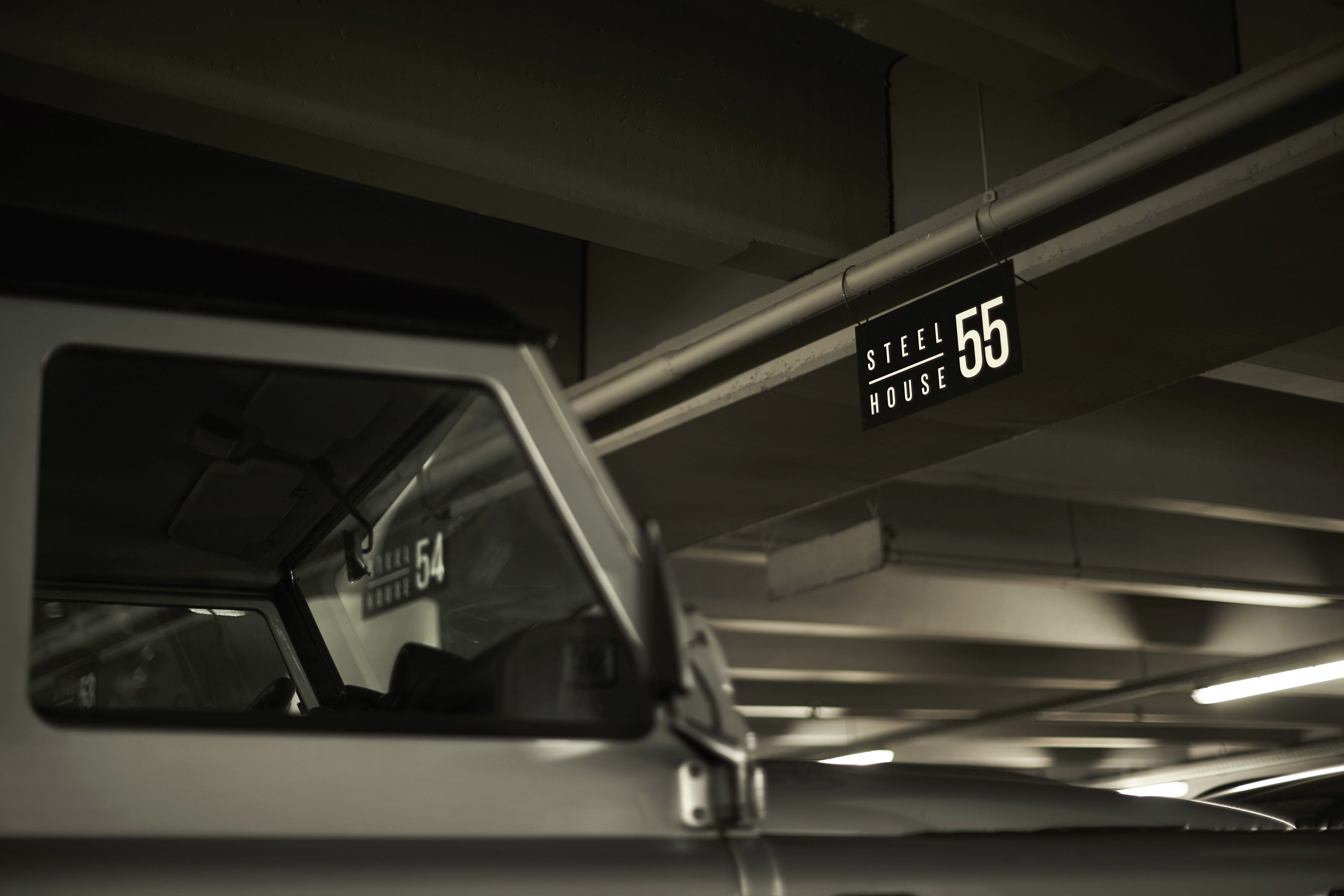 A parking garage with a car parked in a space marked "STEEL HOUSE 55".