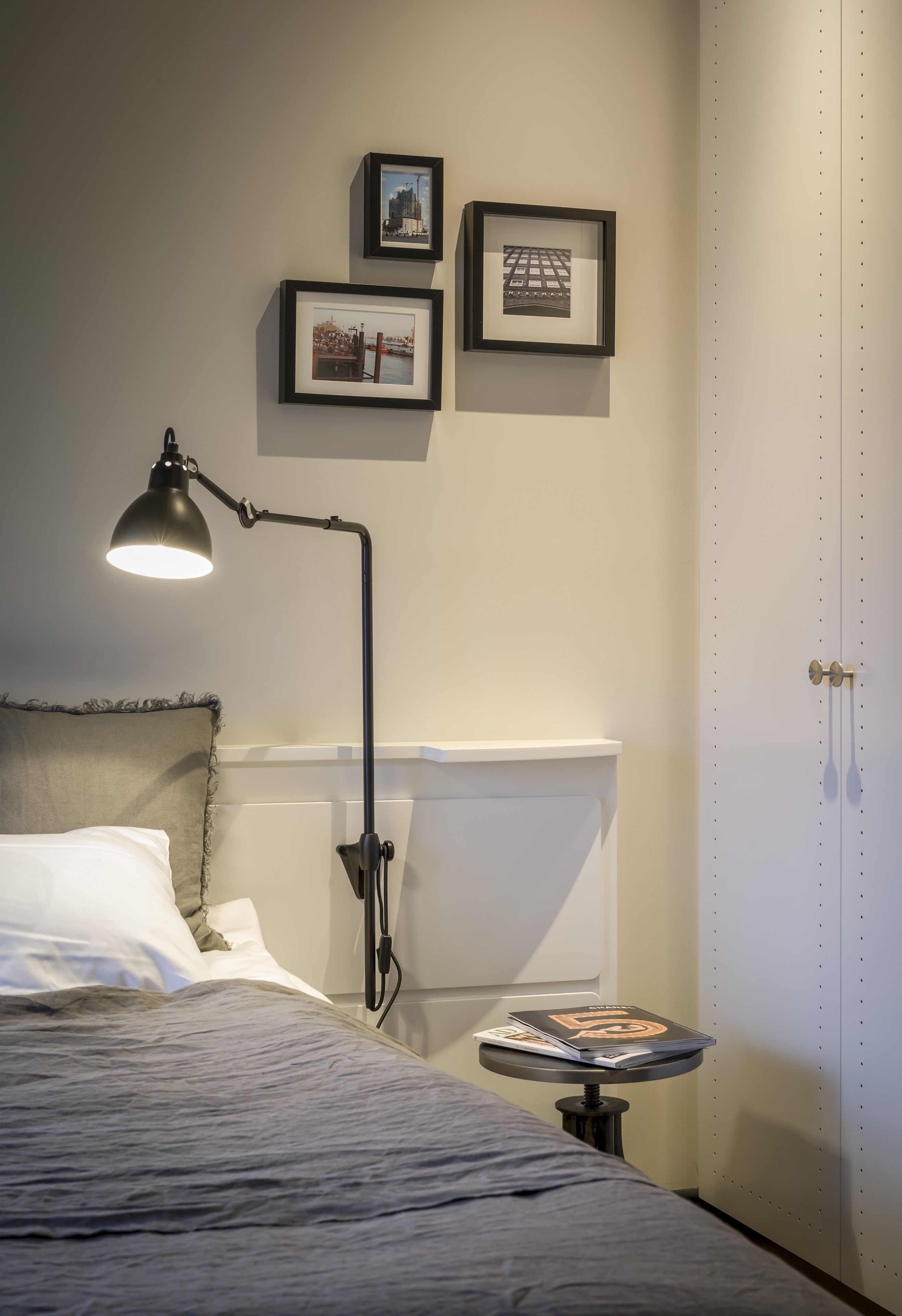 Un dormitorio con una cama, un escritorio con lámpara y cuadros en la pared.