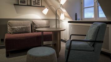 A cozy room with a red patterned sofa, a blue armchair, a round table, and a floor lamp.
