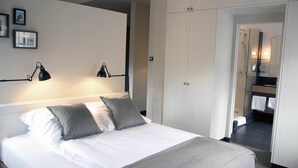 A neatly made bed with two pillows, a bedside lamp, and a wall-mounted picture frame. - Apartment040 (Hamburg)