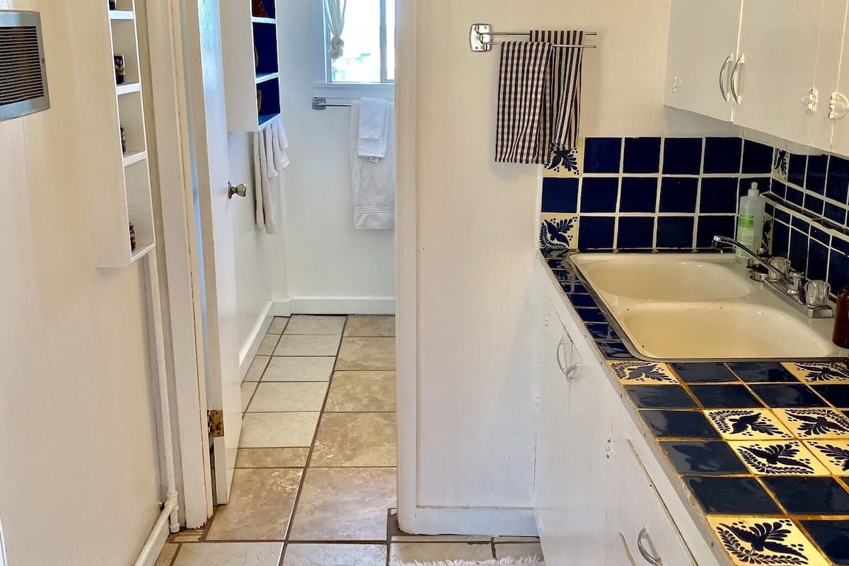 Una cocina con armarios blancos, salpicadero de azulejos, estufa y fregadero.