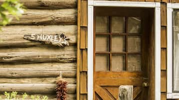 A rustic wooden cabin with a wooden door and a sign that reads "HUXLEY".
