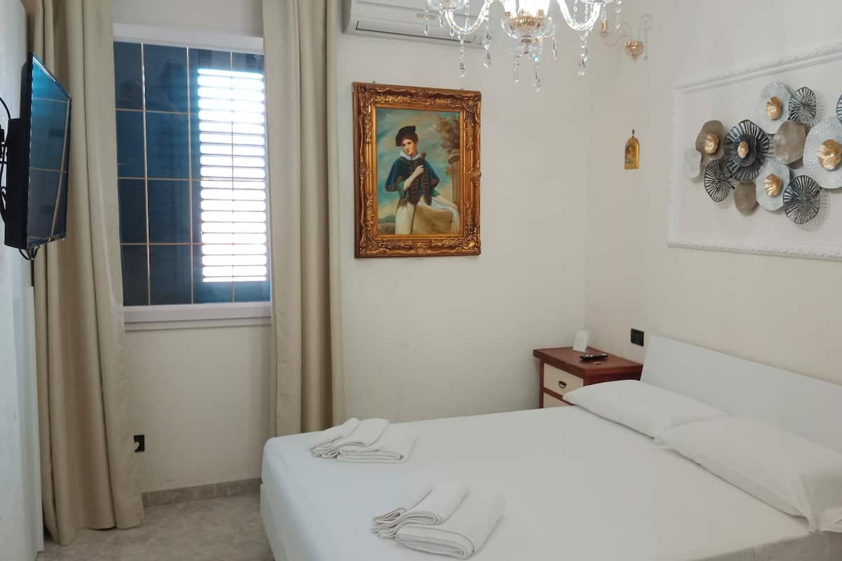 Une chambre d’hôtel avec un lit, une table de chevet, un tableau et un élément décoratif mural.