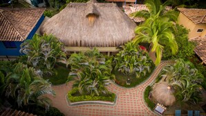 A resort with a central thatched-roof building surrounded by palm trees and a paved walkway. - Hosteria Tonusco Campestre (Santa Fe de Antioquia)